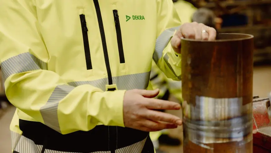 En provningstekniker i gula varselkläder som håller i ett rör.