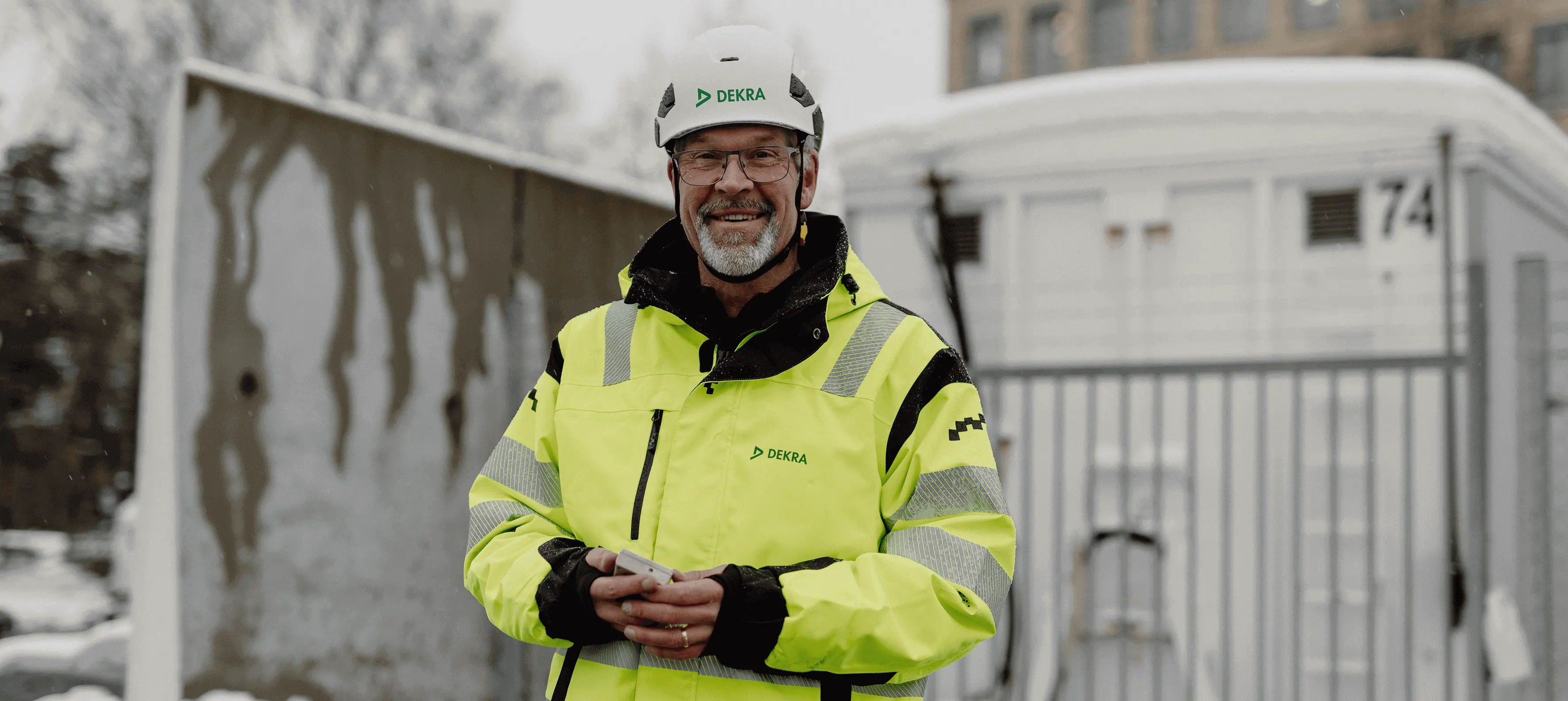 A man in reflective work clothes and white helmet smiling.