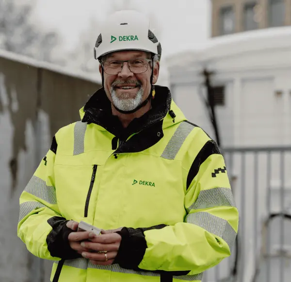 A man in reflective work clothes and white helmet smiling.