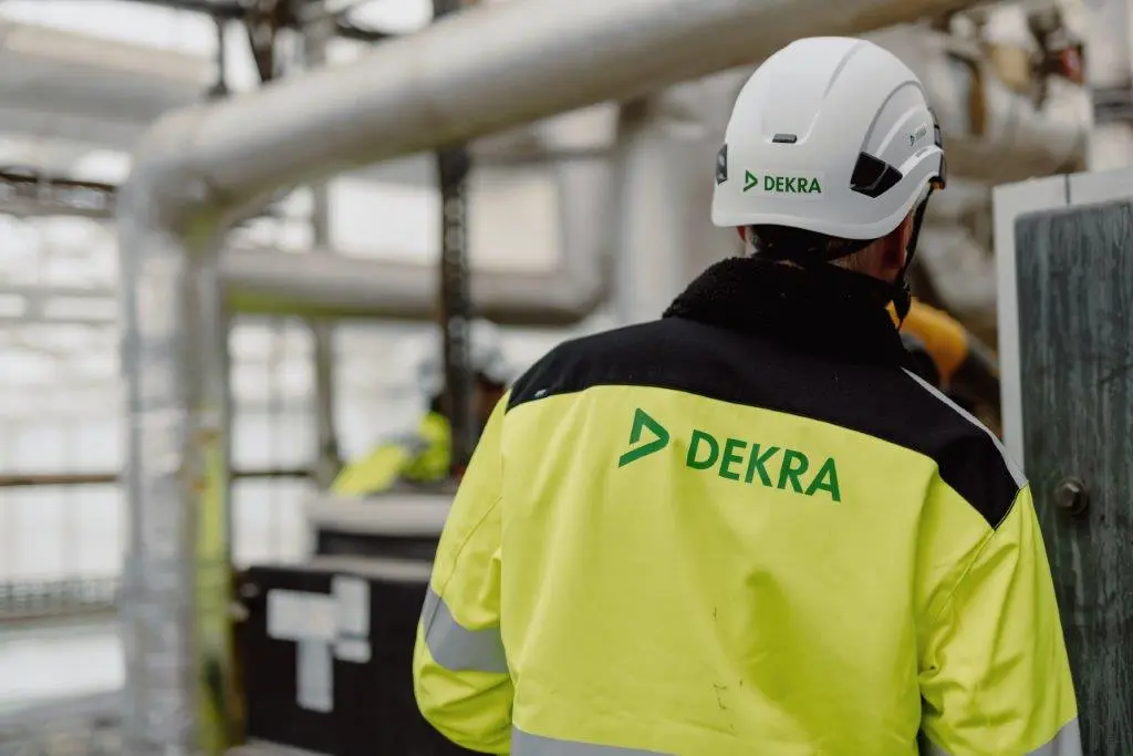 A man in a white hard hat and reflective work clothes, prepared for safety, exemplifying professionalism in a construction environment. 