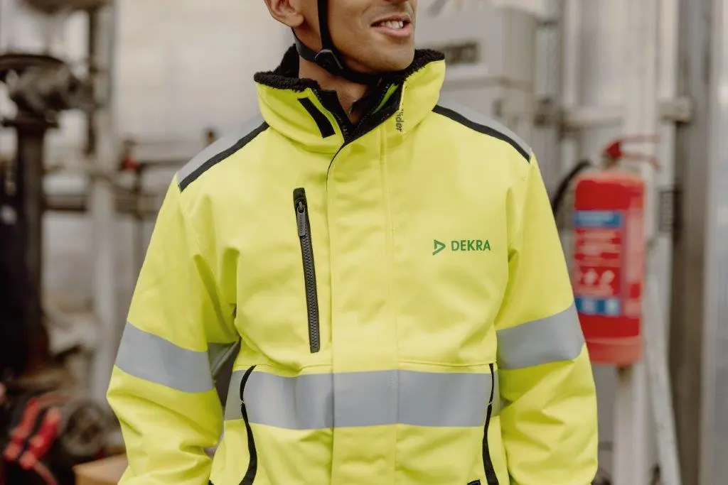 A man in a white hard hat and reflective work clothes, prepared for safety, exemplifying professionalism in a construction environment. 