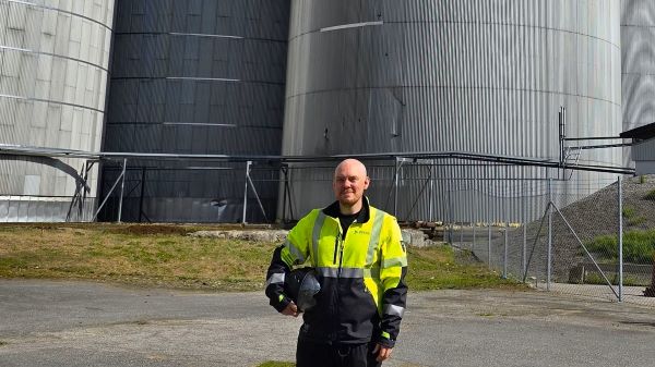 Bild visar en DEKRA-medarbetare som står framför en silo och tittar mot kameran. 