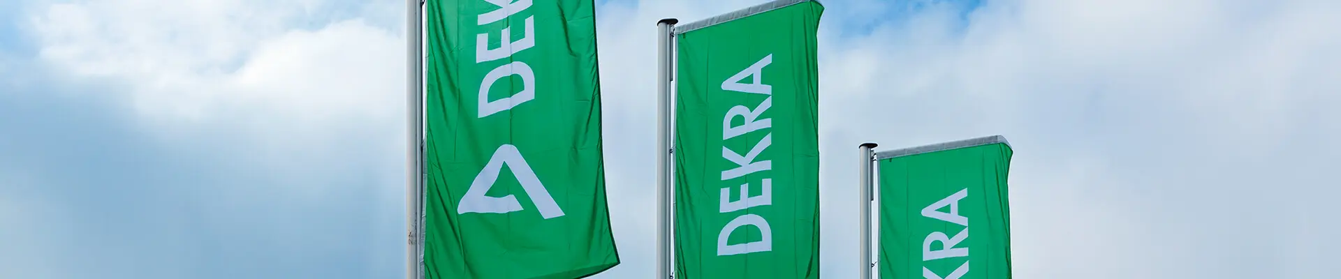 Tre gröna flaggor som det står DEKRA på, himmel som bakgrund.