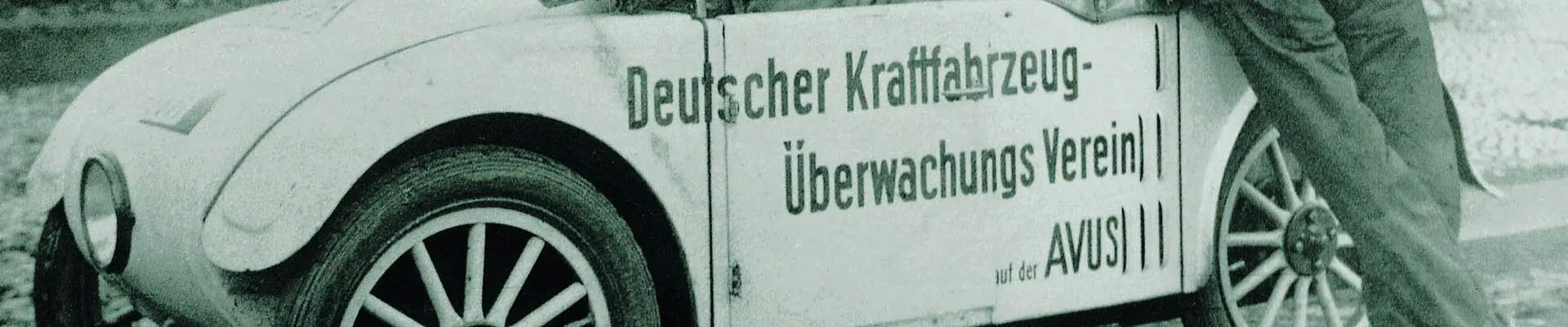 A black and white image of a white retro car with people standing around the car. A black and white image of a white retro car with people standing around the car.