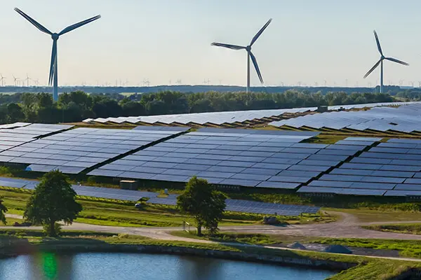 Fields of grass with several wind turbines along the horizon and solar panels along the ground. Fields of grass with several wind turbines along the horizon and solar panels along the ground.