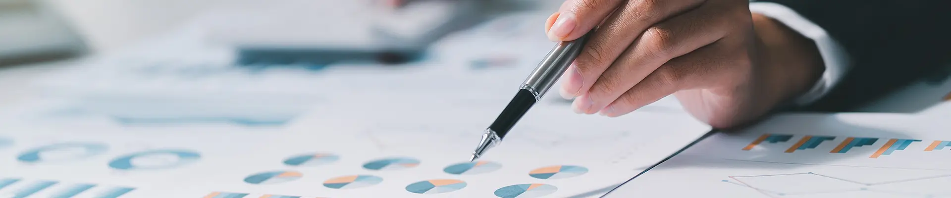 A hand holding a pen and pointing with the pen to paper with diagrams on it. A hand holding a pen and pointing with the pen to paper with diagrams on it.