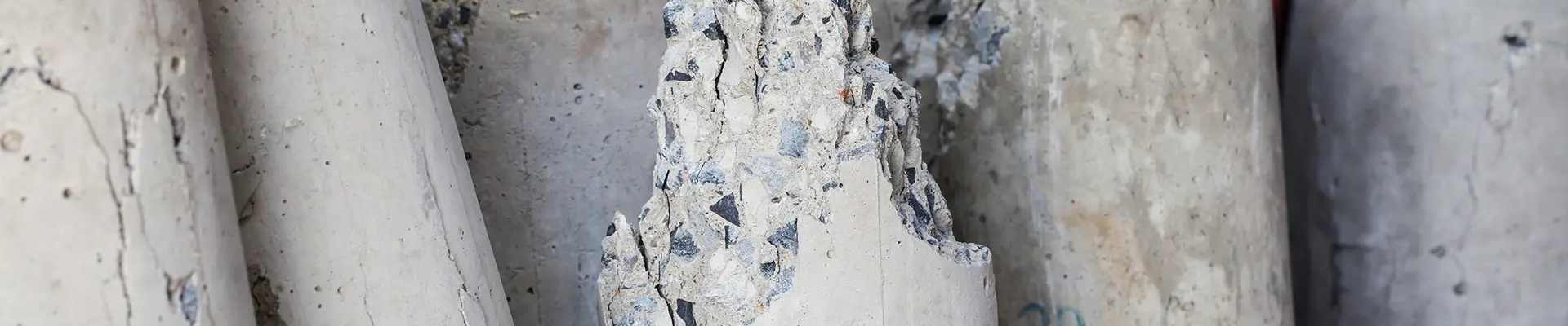 Trasiga smala pelare av betong som ligger på marken.Betong