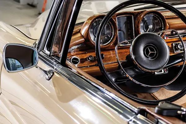 The long side of a retro sand colored car inside a car inspection hall.