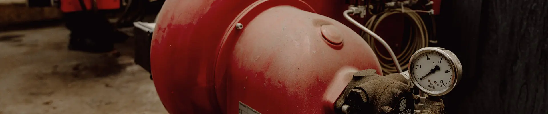 En dammig röd panna med tryckmätare på i en industrilokal. En dammig röd panna med tryckmätare på i en industrilokal.
