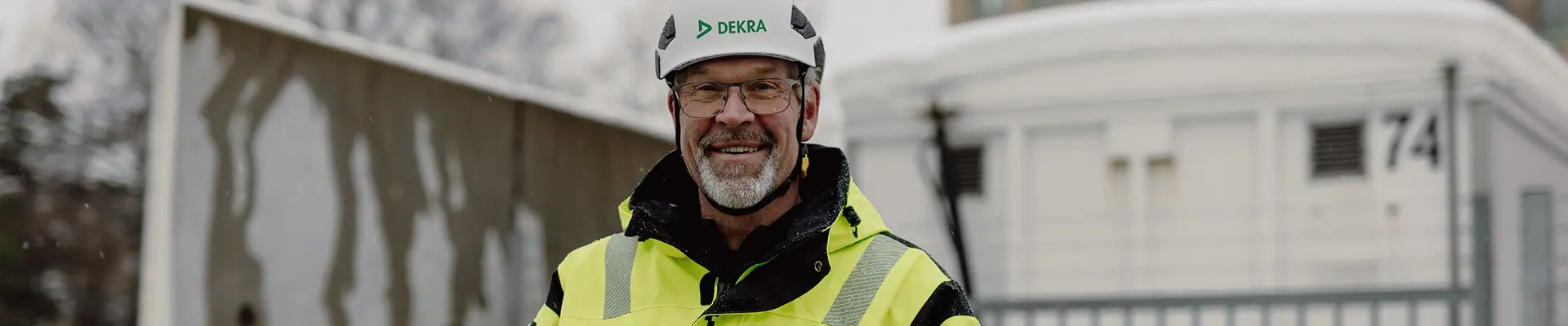 En man i reflexkläder och vit hjälm som ler och tittar in i kameran.