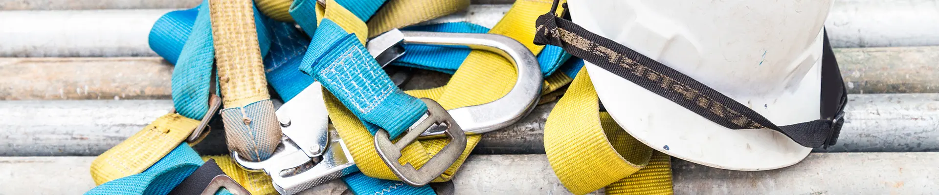Safety equipment, including a harness and a white helmet, placed on metal pipes, highlighting the importance of protective gear when working at heights. Safety equipment, including a harness and a white helmet, placed on metal pipes, highlighting the importance of protective gear when working at heights.
