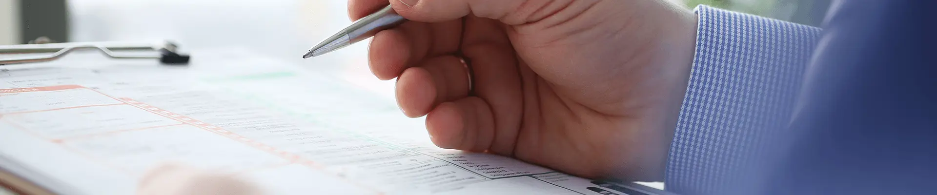 A person diligently writes on a clipboard using a pen, capturing important notes or information.