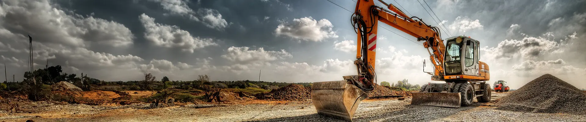 A construction machine positioned beside a train track, ready for maintenance or construction work on the railway.