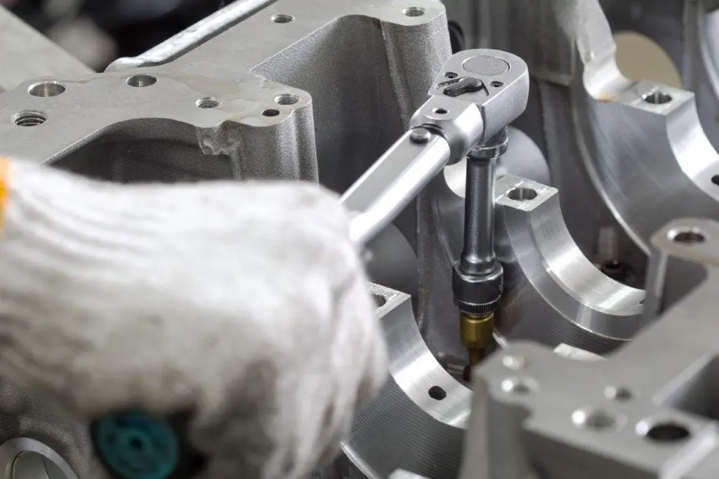 En hand med en grå handske på som håller i en momentnyckel och vrider motsols.