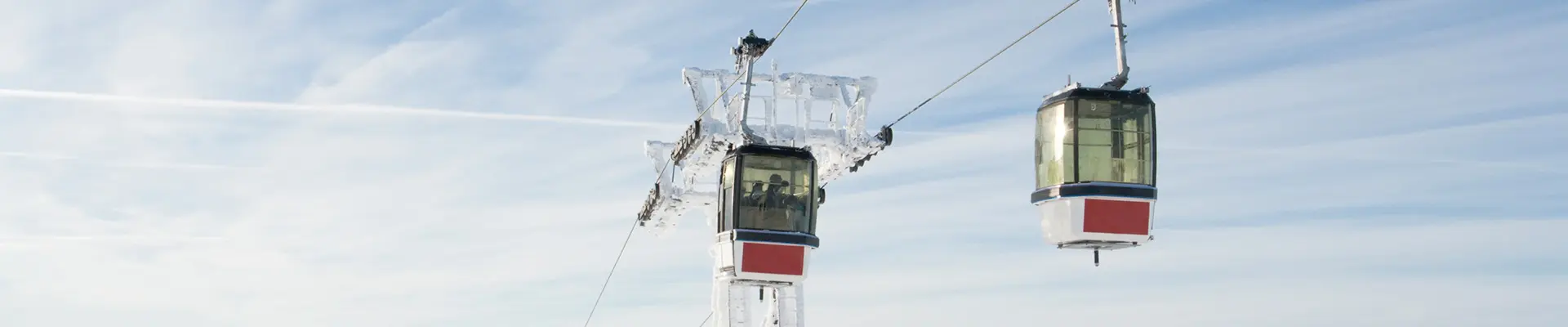 Two ski lifts suspended in the air against a clear blue sky, showcasing a serene winter landscape.