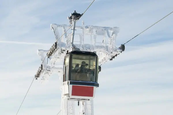 Two ski lifts suspended in the air against a clear blue sky, showcasing a serene winter landscape.