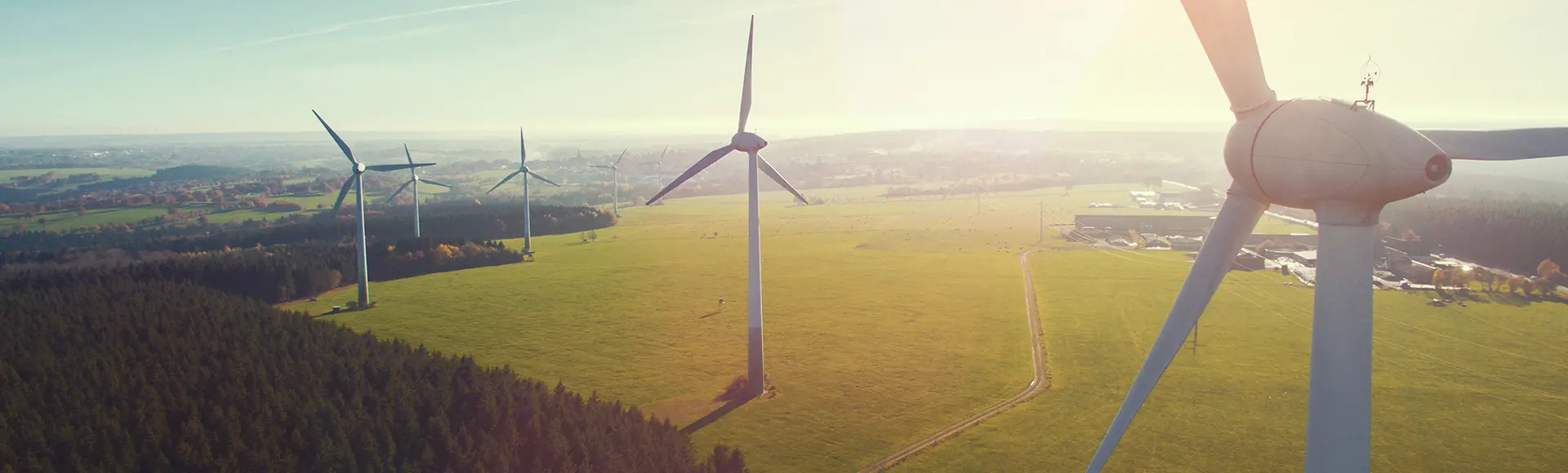 En vindturbin med flera vindkraftverk i bakgrunden på stora fält.
