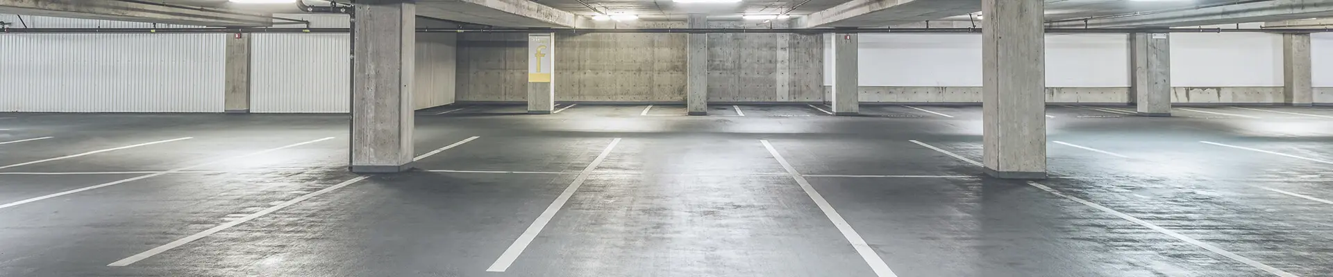 Ett parkeringsgarage byggt i betong med pelare och parkeringsplatser.