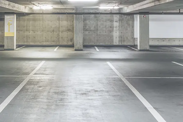 A parking garage built in concrete with pillars and parking spaces.