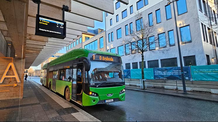 Bild på en grön eldriven ledbuss ståendes på en busstation. 