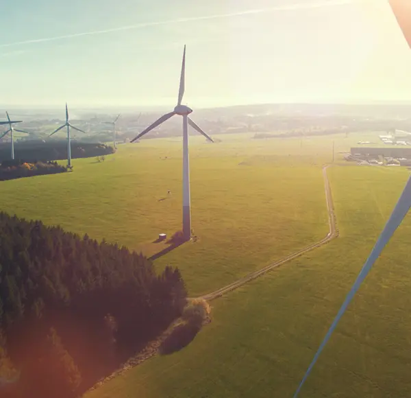 A wind turbine with several wind turbines in the background on large fields.