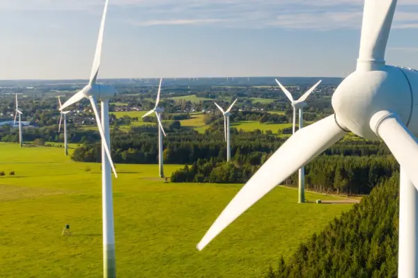 Wind turbines over green fields generating renewable energy supporting sustainable production and ISCC certification.