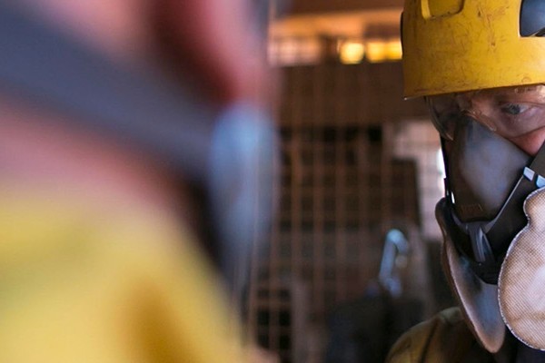 A man in a hard hat and yellow jacket stands confidently, ready for work in a construction environment.