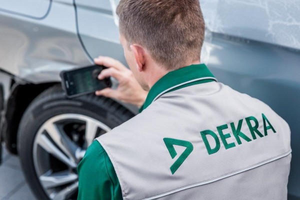 A man in work clothes seen from behind with a car in front.