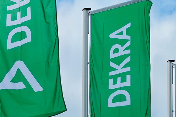 Three green flags that say DEKRA with the sky as a background.