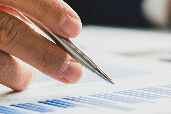 A person writes on a piece of paper while holding a pen, demonstrating the act of note-taking or drafting.