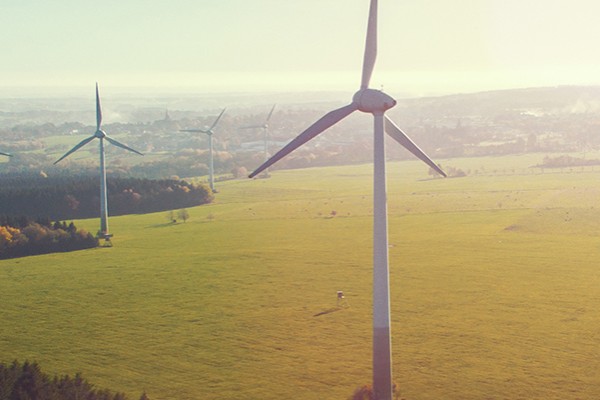 A wind turbine with several wind turbines in the background overlooking large fields.