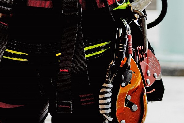 A person wearing a harness and hooks of various types intended for safe climbing.