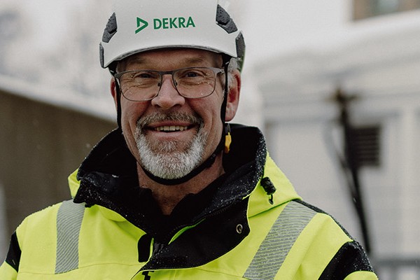 A man in reflective clothing and a white helmet smiling and looking into the camera.