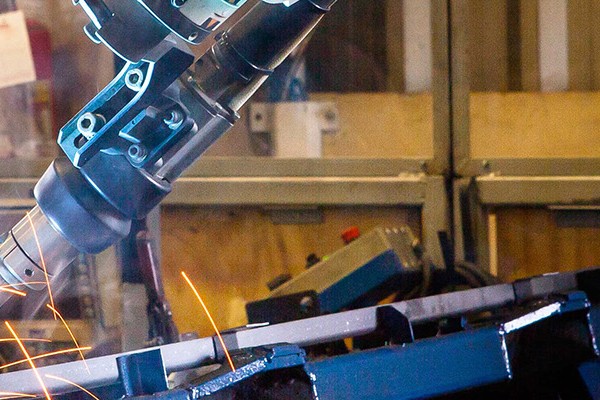 Sparks fly in a metal shop as a welder expertly fuses metal pieces, highlighting the dynamic nature of the welding process.