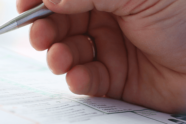 A person diligently writes on a clipboard using a pen, capturing important notes or information.