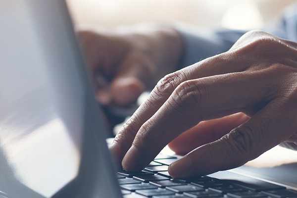 A person's hands typing on a laptop.