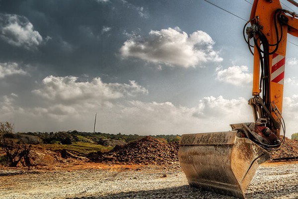 A construction machine positioned beside a train track, ready for maintenance or construction work on the railway.