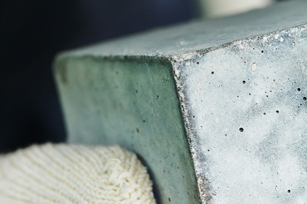 Hands holding a square lump of concrete.