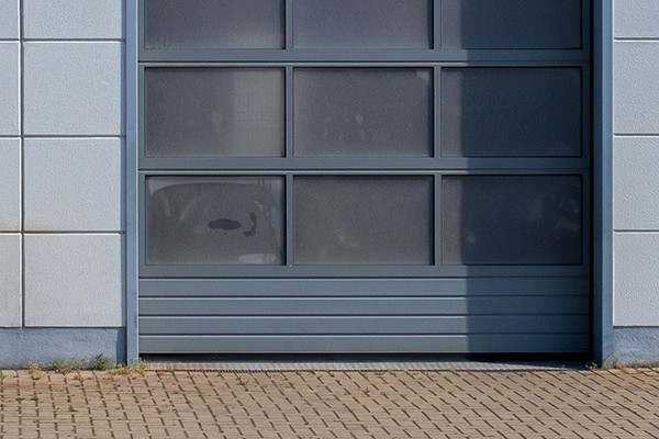 On the gray facade of a house you see three gray garage doors.