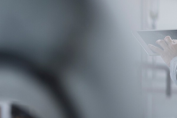 A person carrying out a risk assessment in the work environment wearing a reflective vest with an iPad in hand.