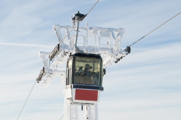 Two ski lifts suspended in the air against a clear blue sky, showcasing a serene winter landscape.