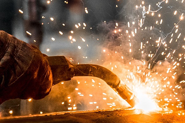 A person's hand holding a welding tool and welding so sparks fly.