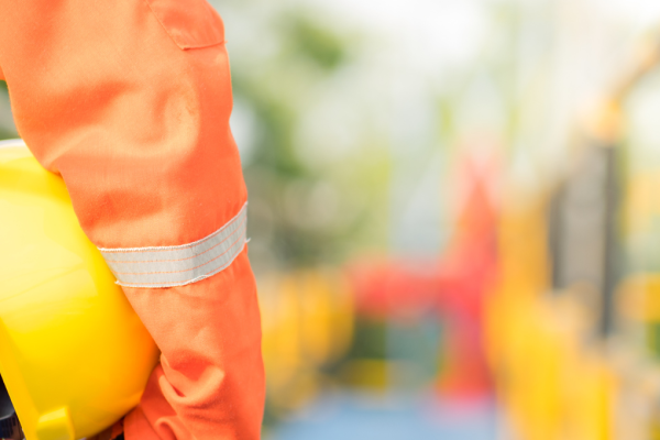 Man in orange uniform holding hard hat