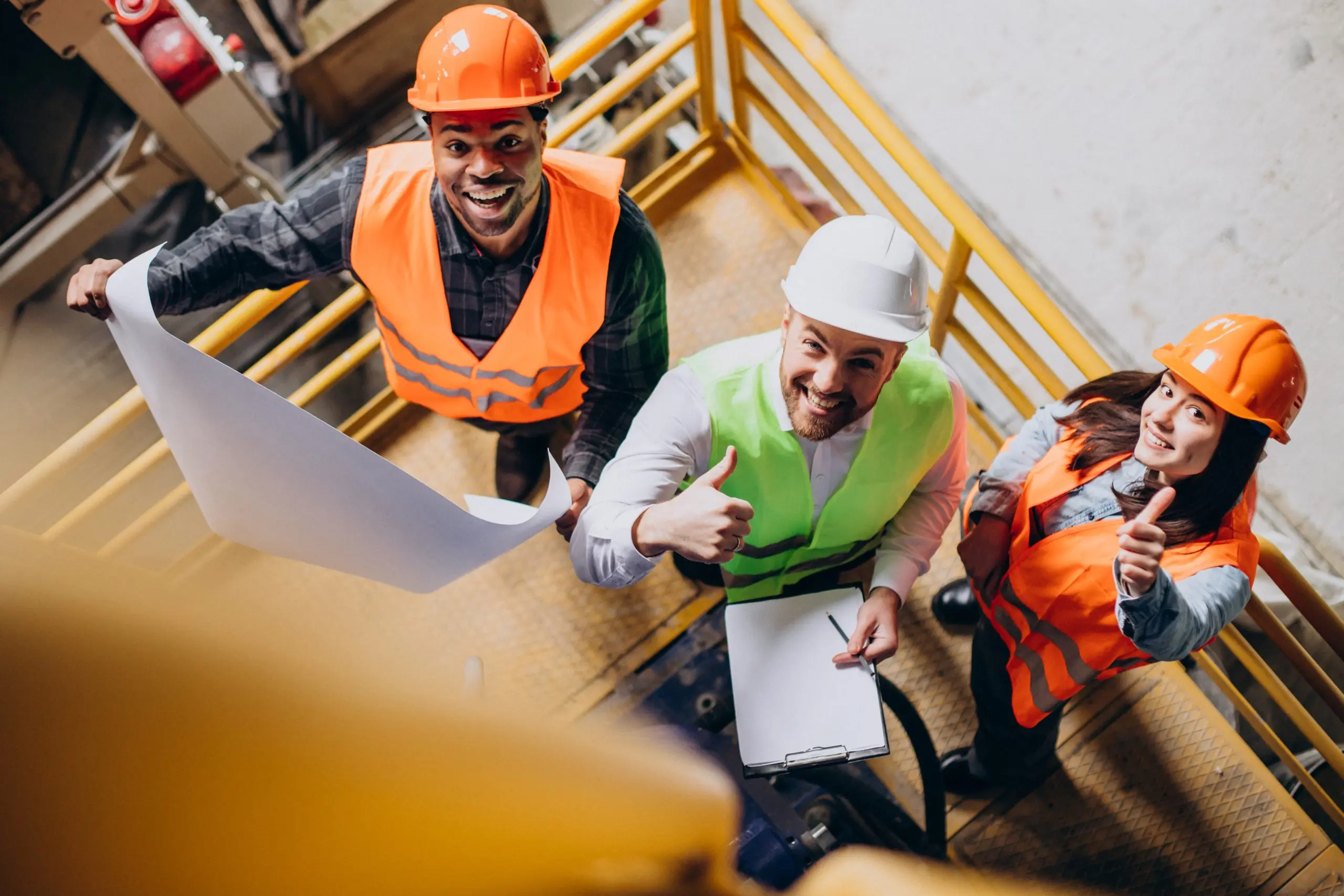 Three factory workers wearing safety hats.